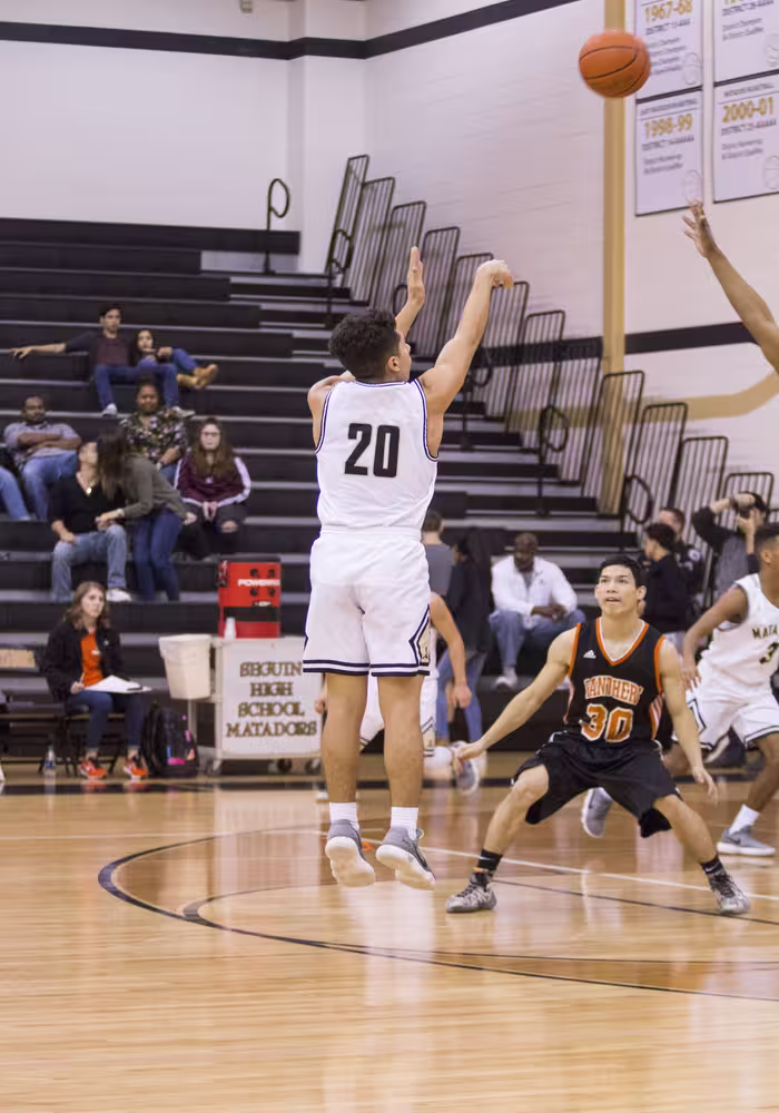 basketball player attempting a three-pointer during a competitive game