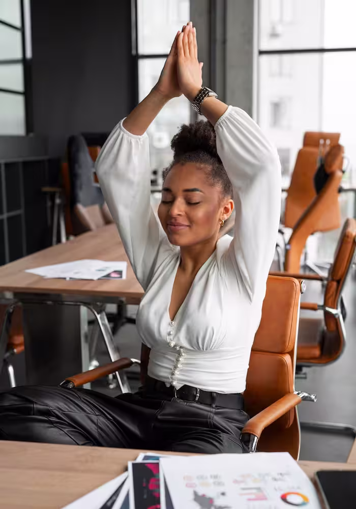 professional girl stretching out, doing a yoga pose while sitting behind her workstation